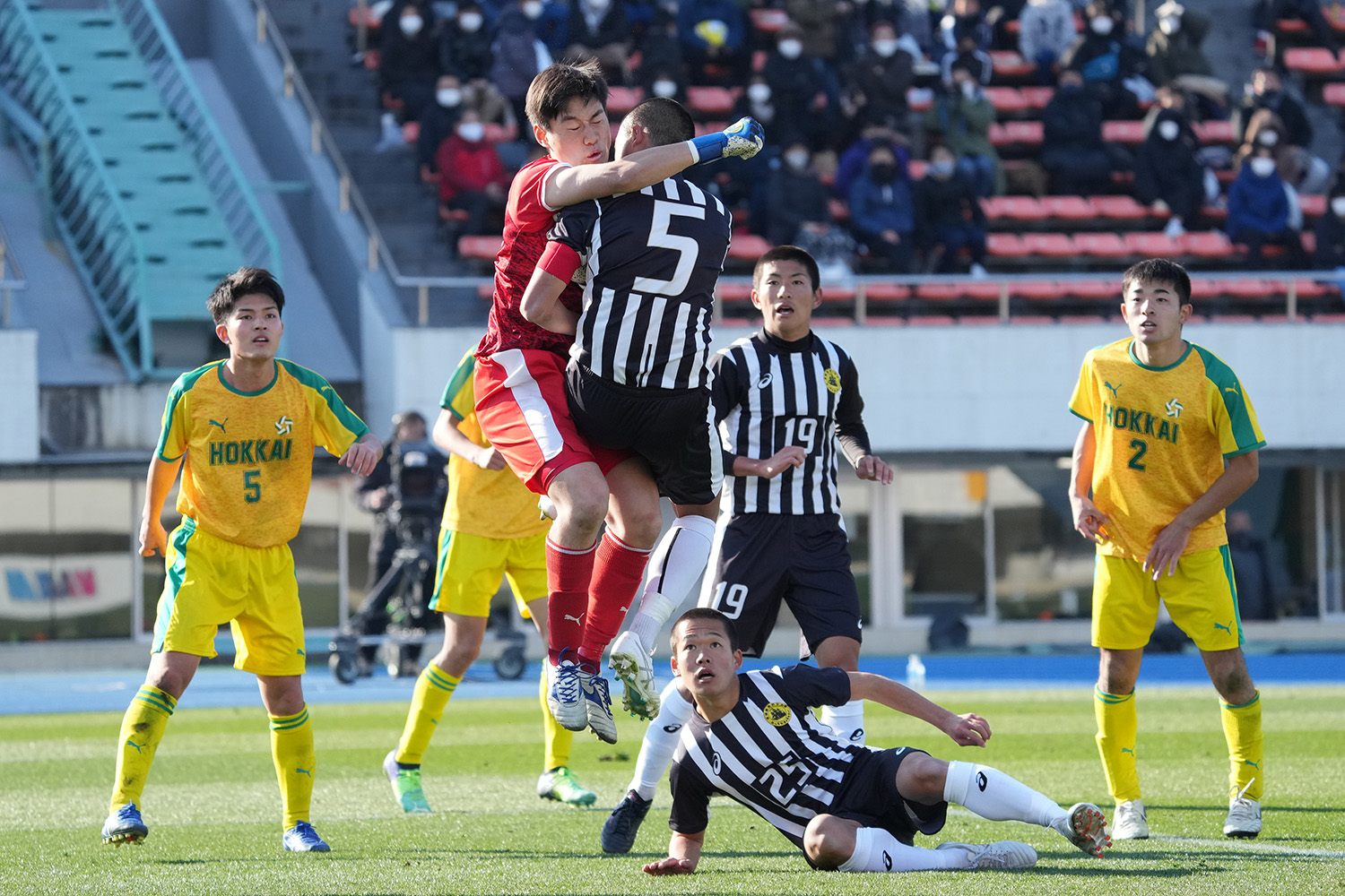 2021年12月29日　1回戦　北海（北海道）vs長崎総科大附（長崎）＝駒沢競技場　サッカーも格闘技のような体と体のぶつかり合いがあります。 GK伊藤麗生選手（北海3年）と、DF児玉勇翔選手（長崎総科大附3年）の空中での体当たりです。このシーンは、キャプテン同士のぶつかり合いでもありました。周りの選手が同じような表情で見ているのも面白いです。