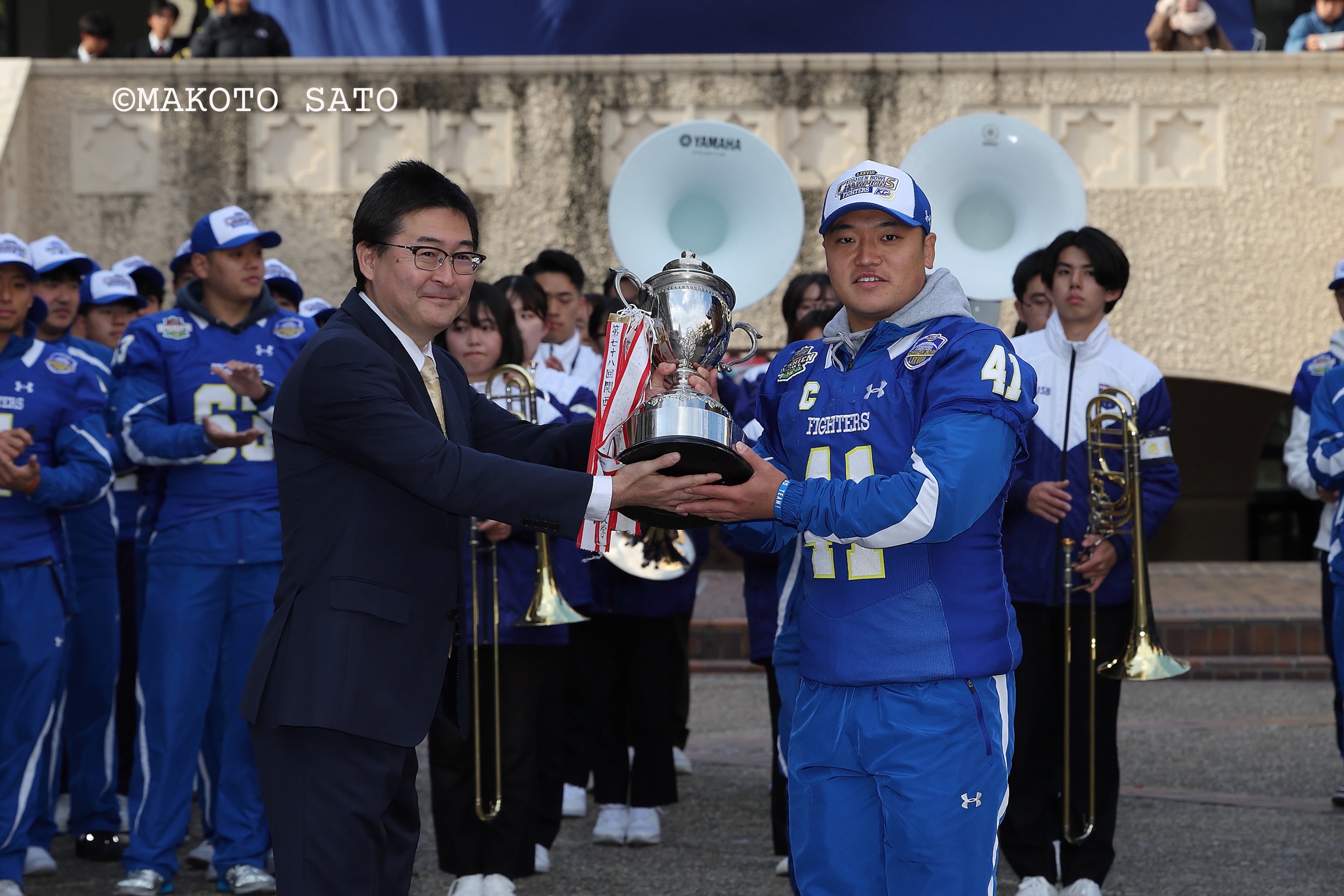 優勝祝賀セレモニーで本郷亮学生部長からトロフィーを受け取る海﨑琢主将 写真:佐藤誠