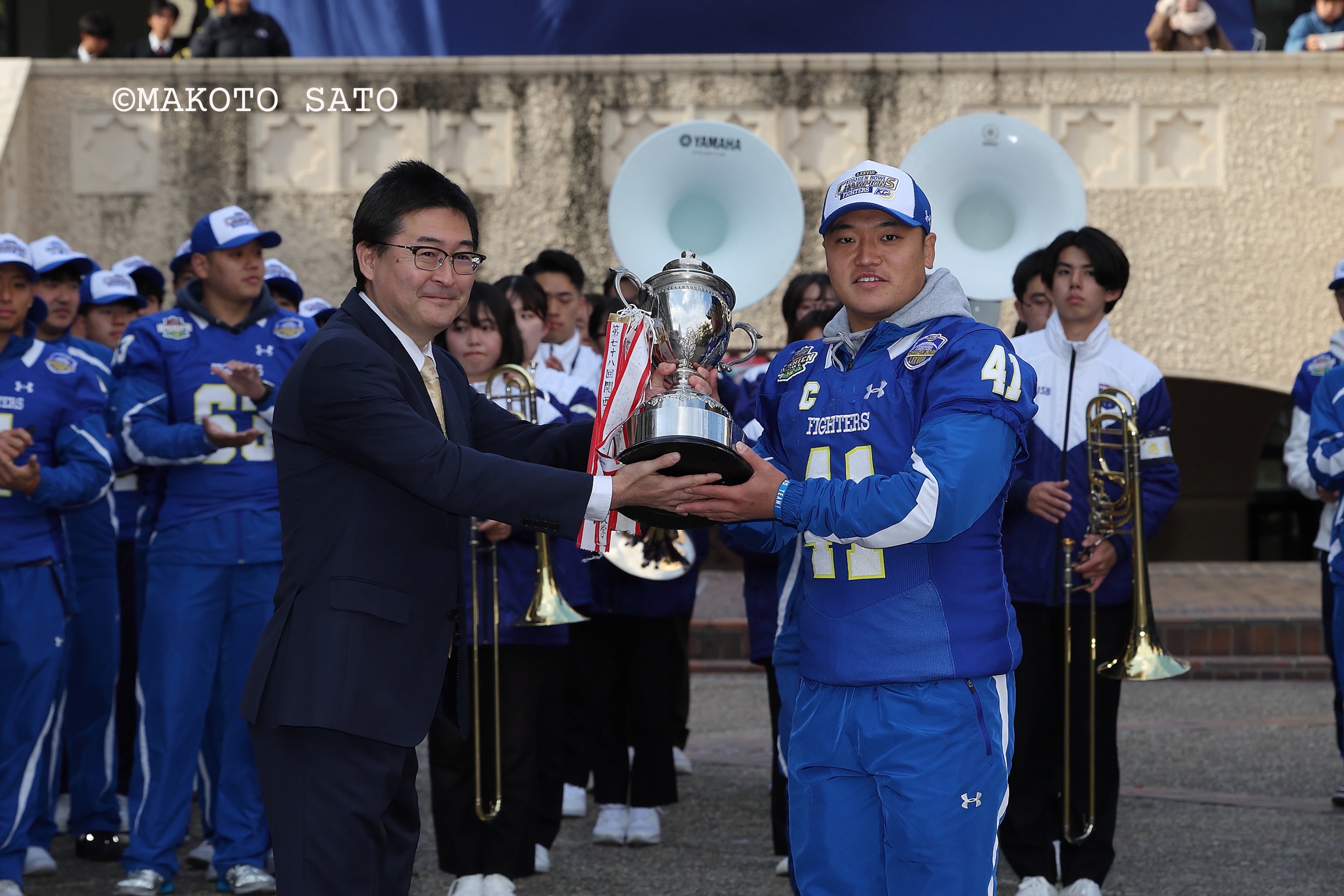 優勝祝賀セレモニーで本郷亮学生部長からトロフィーを受け取る海﨑琢主将　写真：佐藤誠