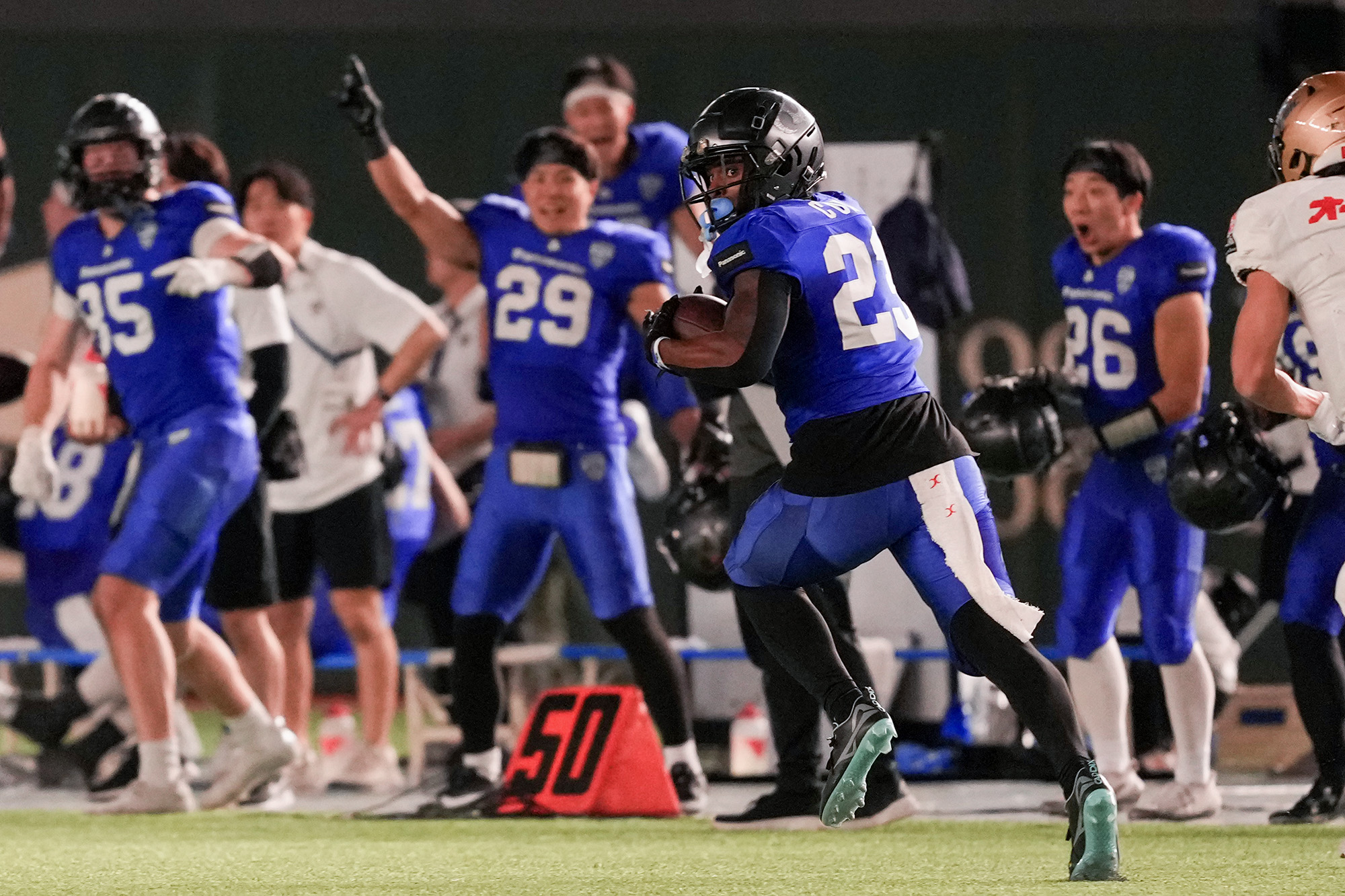 2本目のINTを決めて勝負を決定づけたパナソニックDBコックス。背後から猛烈に追いすがるオービックWR佐久間にタックルされてTDはならず=撮影：北川直樹