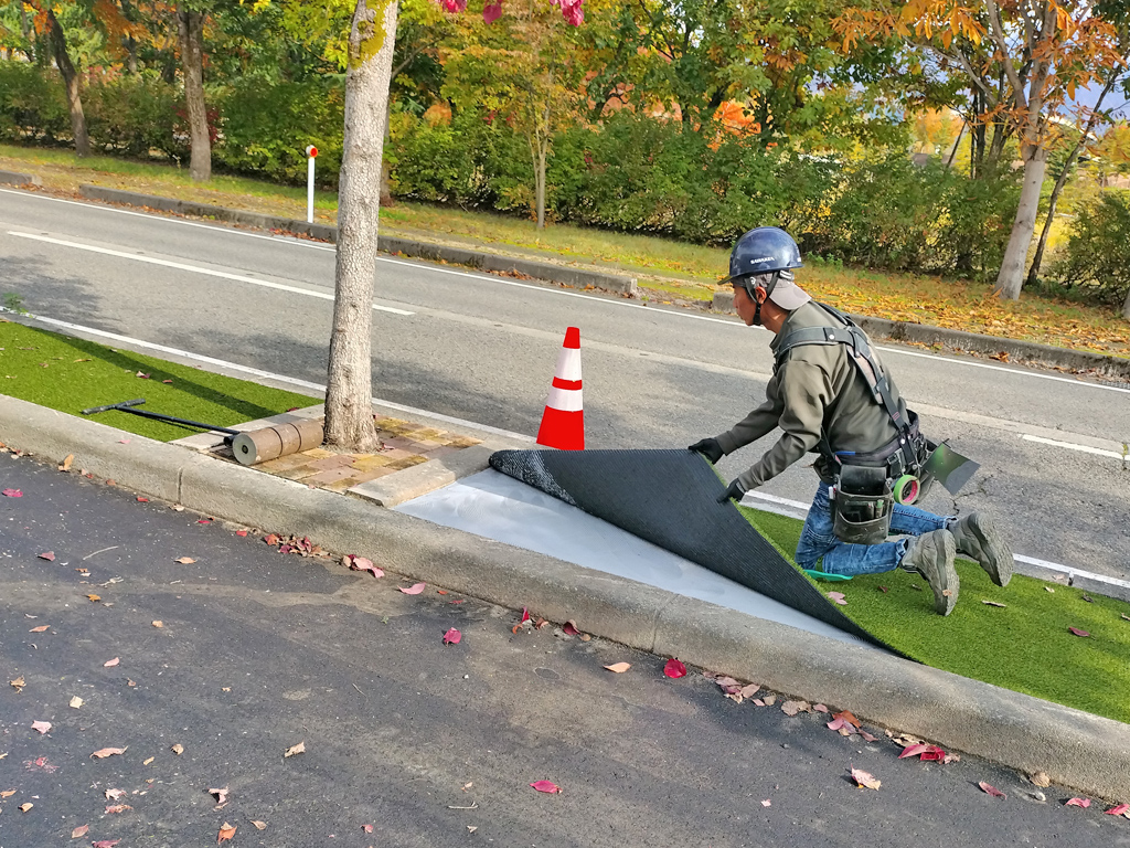 コンクリートに接着剤を塗り終えたら、めくっていた人工芝を下ろして貼り付ける